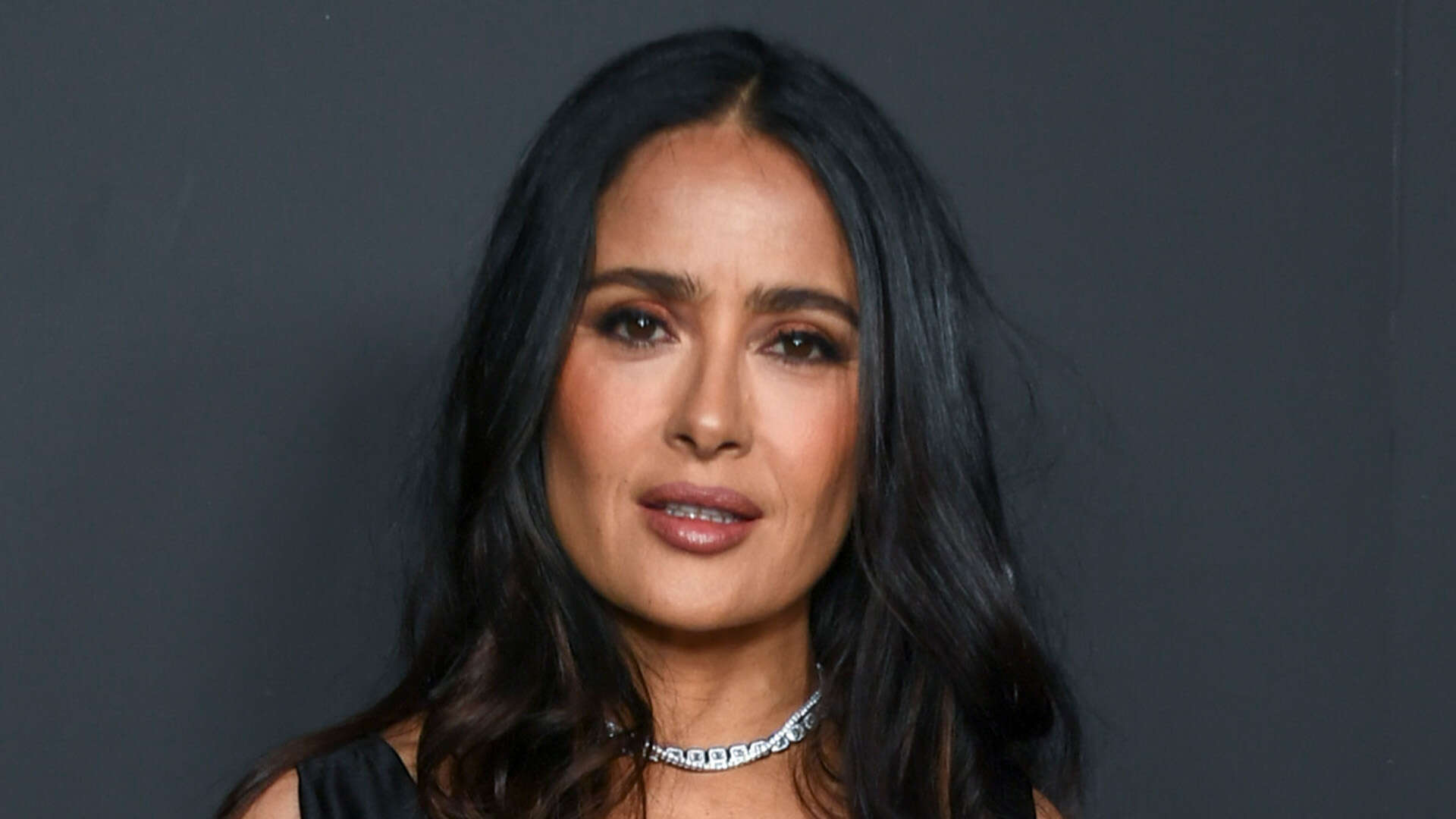 Salma Hayek, 57, shows off her curves in skintight black dress and looks ageless at Oppenheimer Oscars event in LA