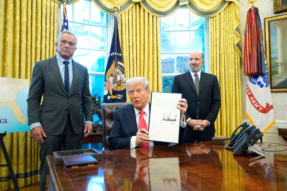 RFK Jr looks less than thrilled asTrump hawks merch in the Oval Office