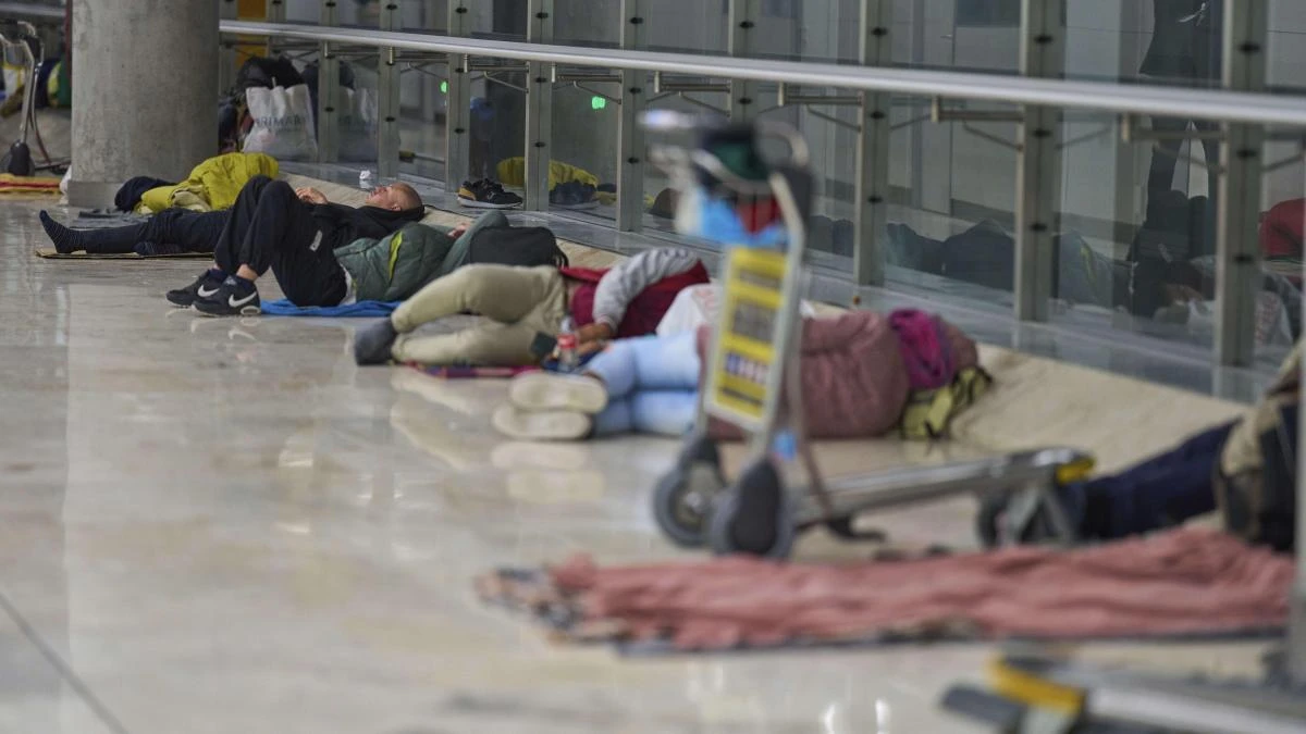 Las personas sin techo se trasladan al parking de la T-4 por los controles de acceso en Barajas