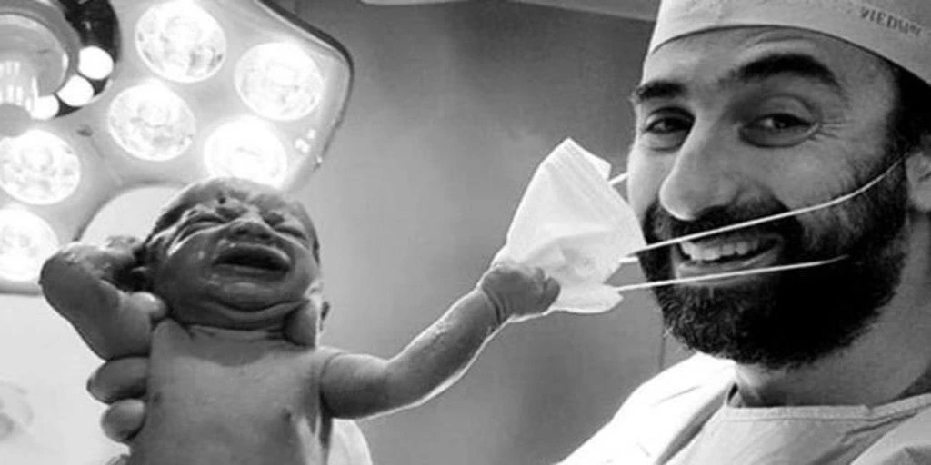 Un recién nacido da la vuelta al mundo por arrancar la mascarilla a su médico tras el parto: «La foto del año»