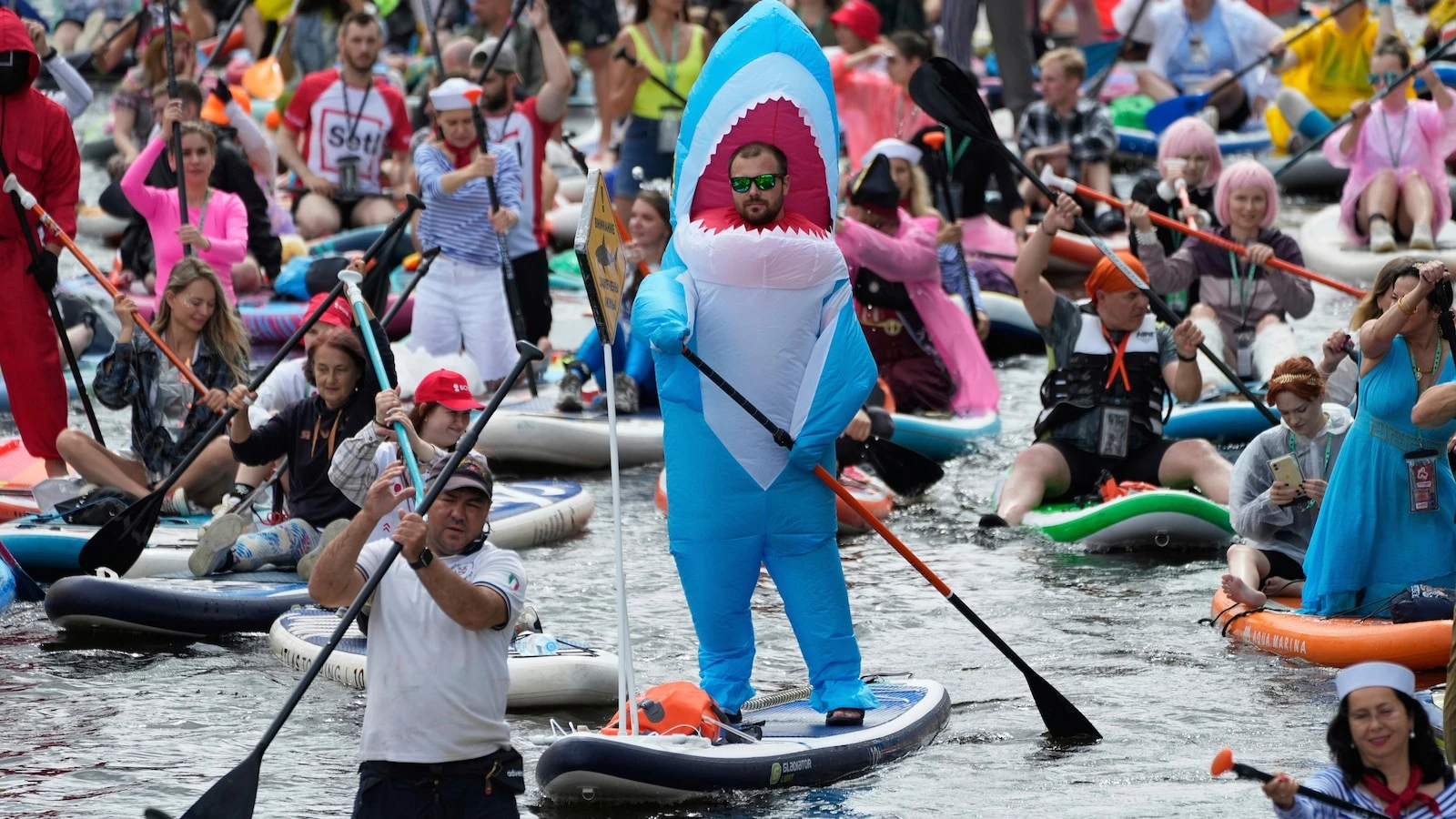 Photos show costumed participants steer stand-up paddle boards at a festival in Russia