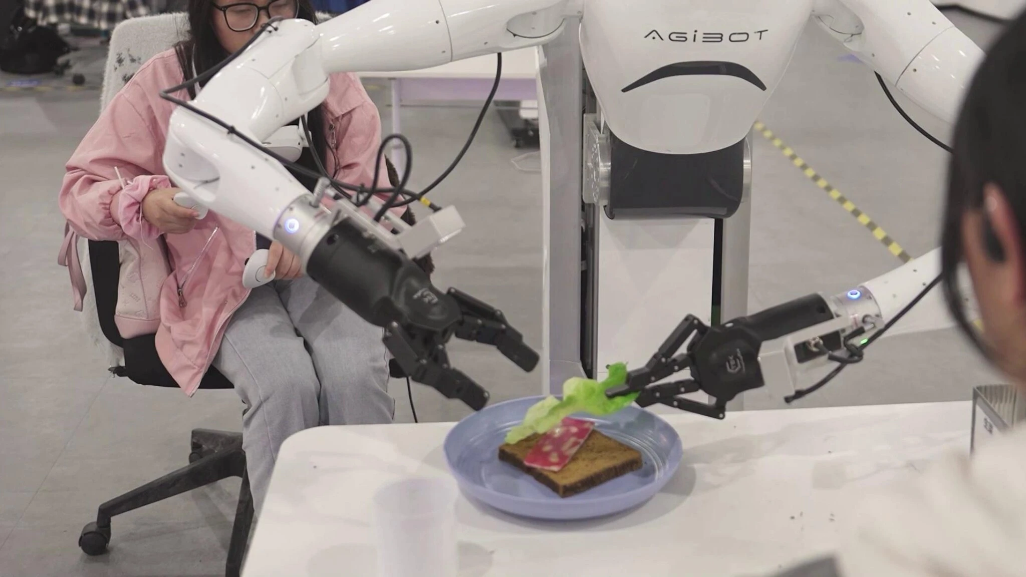 Il robot cinese che prepara un panino al salame, poi indossa una sciarpa: il video