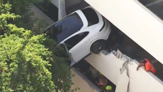 Woman rescued as crash leaves Porsche dangling from parking garage