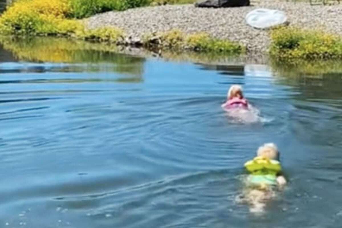 Familie lässt kleine Kinder in Teich baden, im Wasser schwimmt aber auch noch etwas anderes