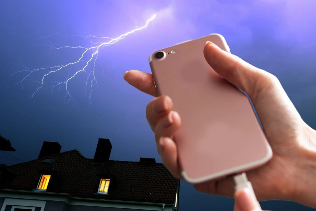 Frau hält Handy beim Laden in der Hand und wird durch Blitzschlag verletzt