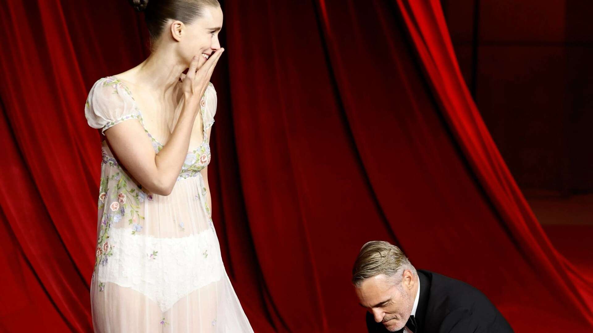 Joaquin Phoenix fixes blushing Rooney Mara's dress at Academy Gala red carpet