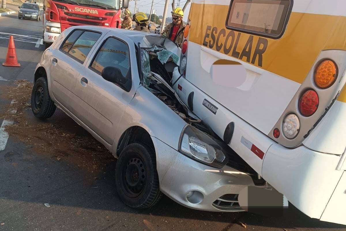 Carro para embaixo de ônibus escolar e fica esmagado em batida no DF