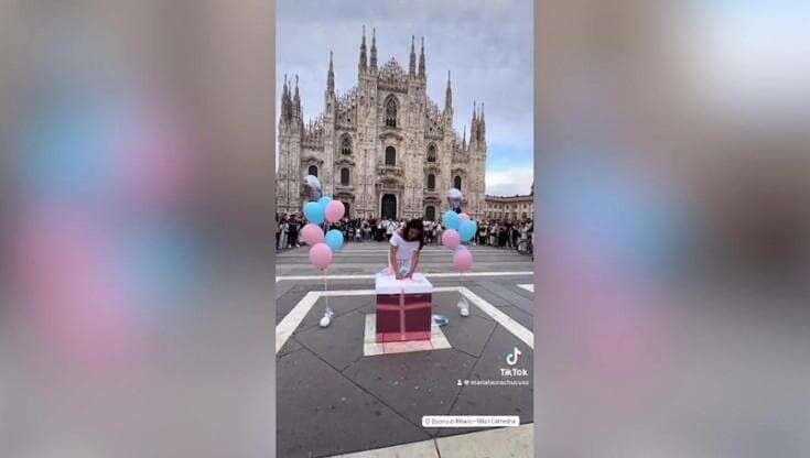 Il gender reveal in piazza Duomo a Milano: turisti e curiosi assistono al momento in cui una coppia scopre il sesso del figlio