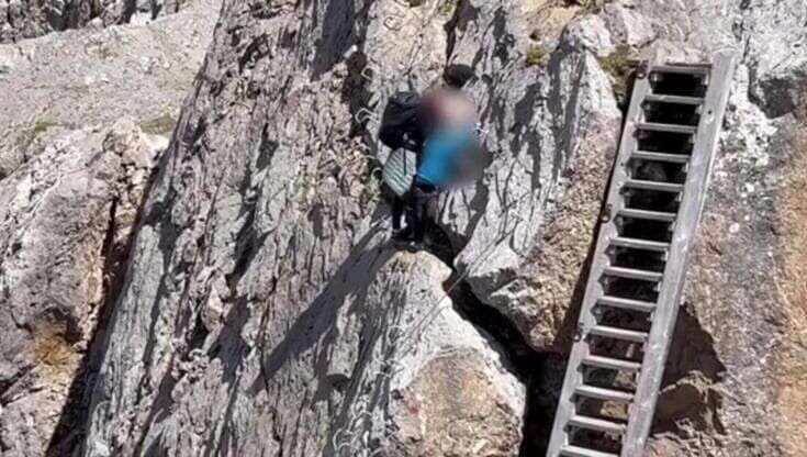 Dolomiti, senza attrezzatura sulla strada ferrata con il piccolo in braccio