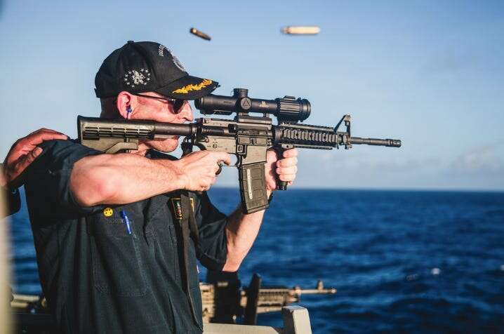 A US Navy warship commander was relieved of duty over a 'loss of confidence' 4 months after he was photographed firing a rifle with a backward scope