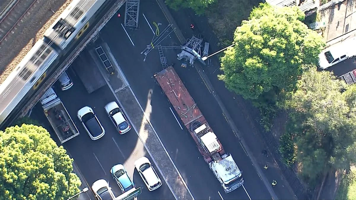 Crane crashes into rail bridge causing peak-hour delays in Sydney