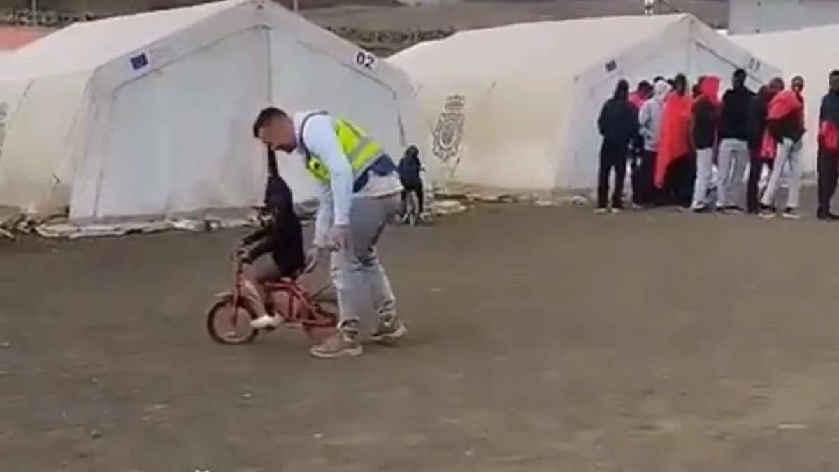 Un policía enseña a un niño migrante a montar en bicicleta en un centro de El Hierro