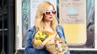 Addison Rae rocks shortest skirt ever, tall suede boots and bra top as she holds flower bouquet for dinner in LA