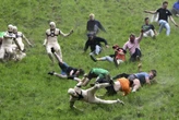 AP PHOTOS: Runners trip, stumble and roll their way to victory in annual downhill cheese chase