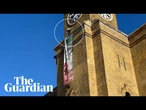 'Freedom for Iran' protester on top of Kings Cross station holding dog