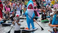 Photos show costumed participants steer stand-up paddle boards at a festival in Russia