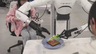 Il robot cinese che prepara un panino al salame, poi indossa una sciarpa: il video