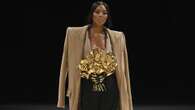 Naomi Campbell sfila per Balmain: le braccia finte reggono un bouquet di fiori d’oro