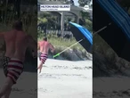 Man in USA bathing suit chases after beach umbrella ahead of July 4th