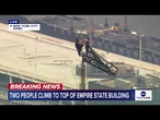 Two people climb to the top of Empire State Building spire, unfurl banner