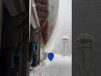 Residents knock down a huge slab of snow off their roof