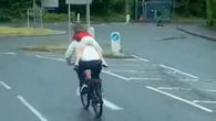 Moment cyclist with child clinging to back goes WRONG WAY through roundabout