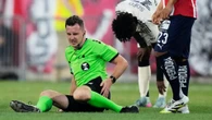 Referee helped off pitch by doctors and grimaces in pain after suffering injury