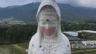 Drone films crew putting giant mask on statue