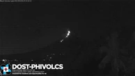 Moment meteor flies through sky beside erupting volcano