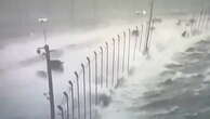 Cars drive across Tampa bridge as Hurricane Helena waves crash on road