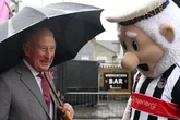 Charles braves downpour to meet football club’s mascot