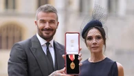 Sir David Beckham smiles next to Lady Victoria Beckham after being knighted