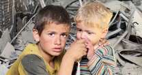 As crowds surge for bread in Gaza, a boy helps his younger brother to drink