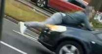 Moment angry man drives off with road rage rival clinging to car bonnet