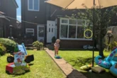 Mum spooked by haunted house and ghostly figure watching over toddler son playing in the garden