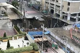 Massive sinkhole opens up right next to hospital and swallows police car as people flee