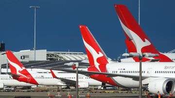 Hundreds of Qantas workers walk off the job on massive travel day