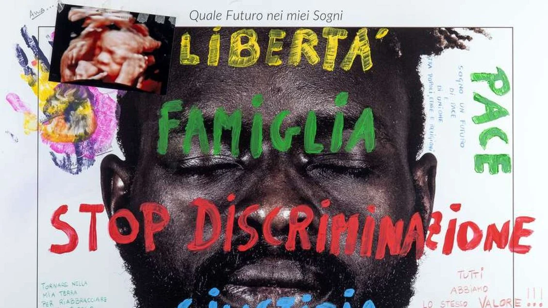 Sulle vetrine dell'Aquila i volti e sogni di 26 migranti