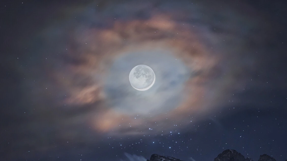 Un'aureola di nuvole per la Luna sopra le cime delle Dolomiti