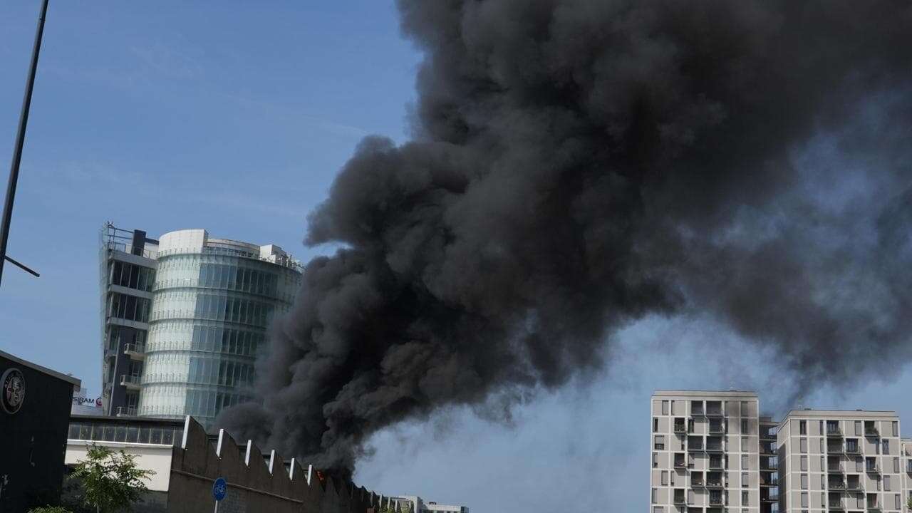 A fuoco il concessionario d’auto DeniCar in via Bisceglie a Milano: la colonna di fumo nero riempie il cielo