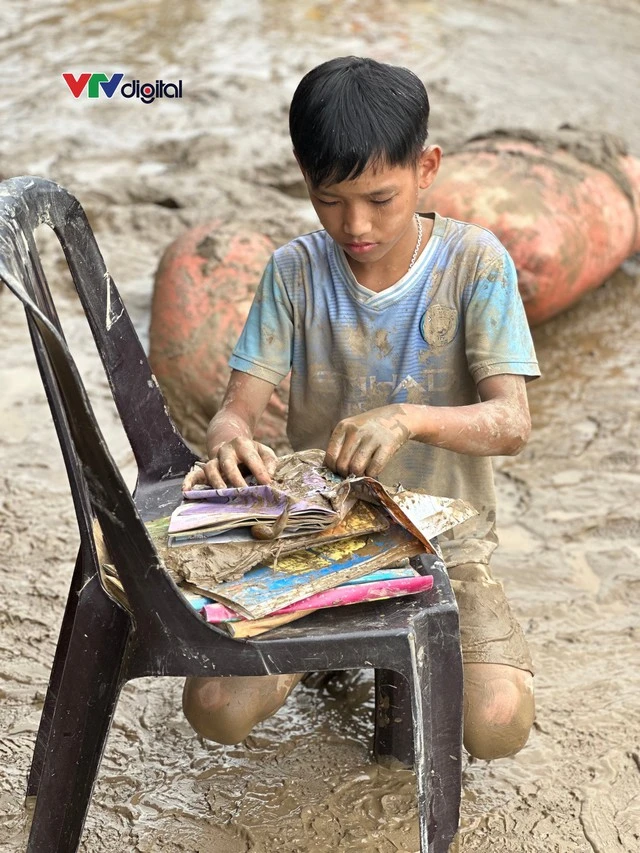 Cậu bé 12 tuổi lật từng trang sách lấm bùn sau lũ quét ở Nghệ An: “Chữ vẫn còn đọc được cô ạ!”