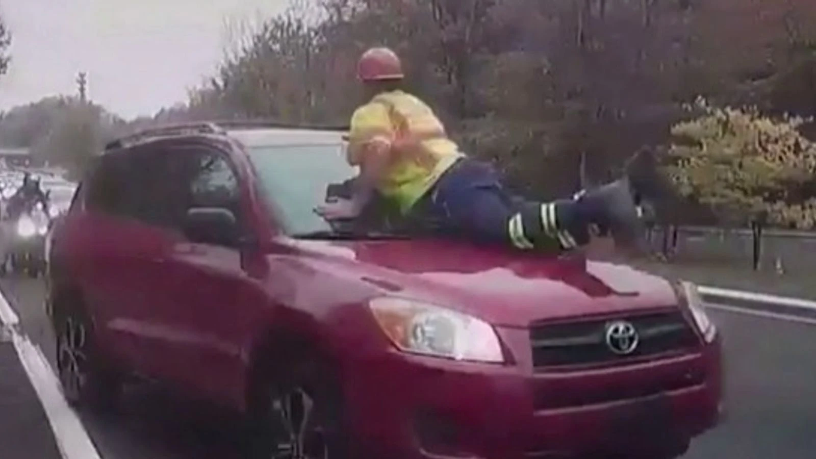 Car driven off with road worker on bonnet