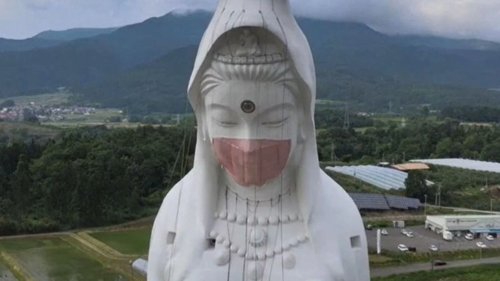 Drone films crew putting giant mask on statue