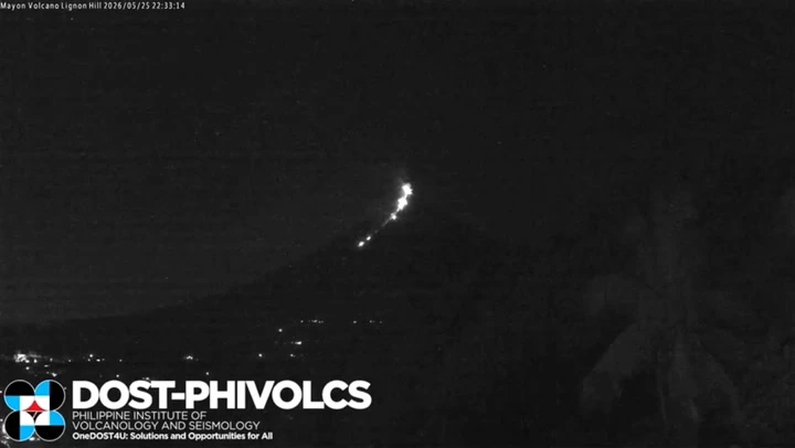 Moment meteor flies through sky beside erupting volcano