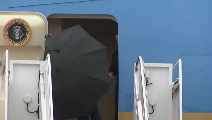 Trump struggles to take down umbrella during storm