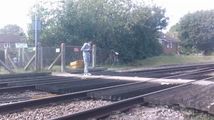 Watch: Distracted teenager stops on train tracks to check phone