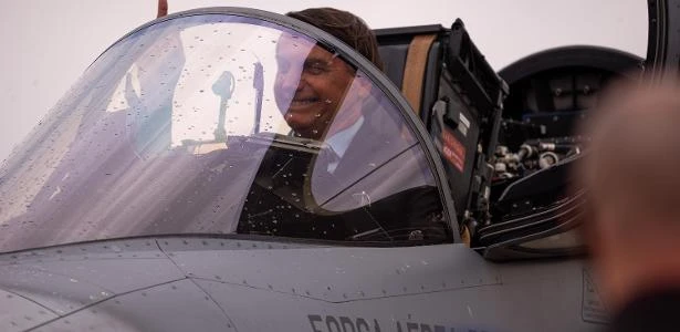 Bolsonaro ensaia bebericar champanhe e pede para entrar em novo caça da FAB