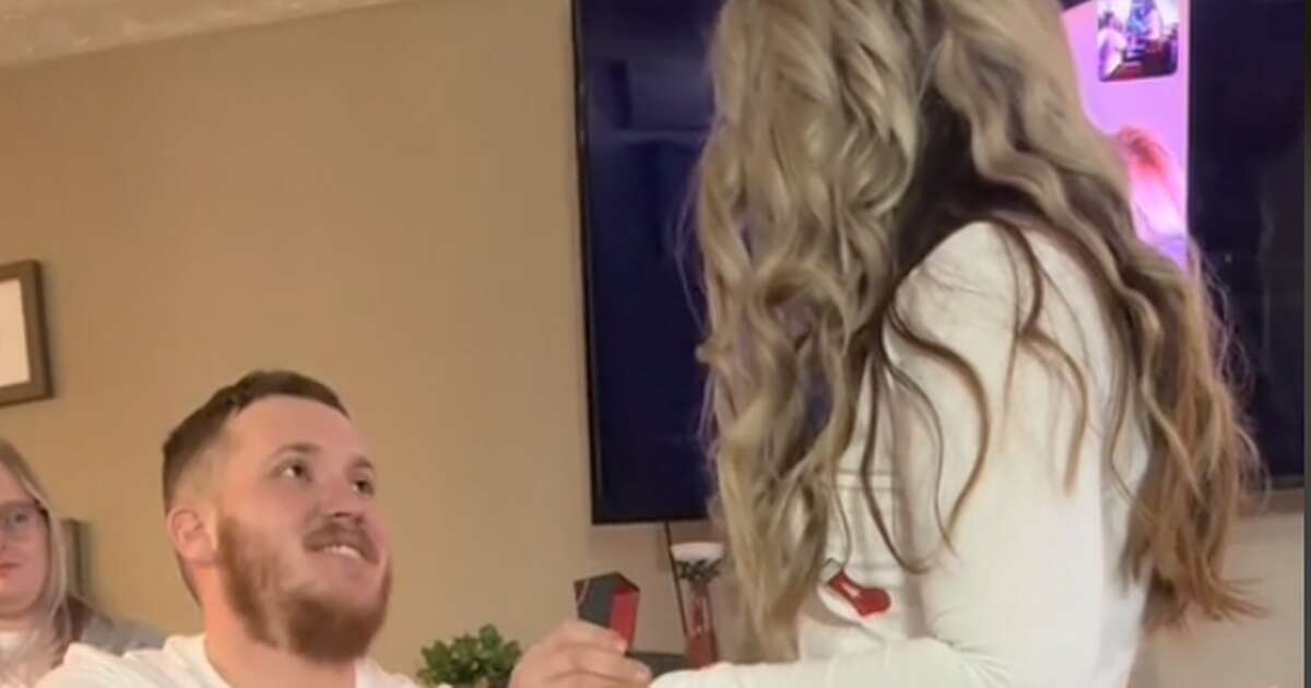 Romantic proposal has people in stitches as they can't help staring at what's behind them