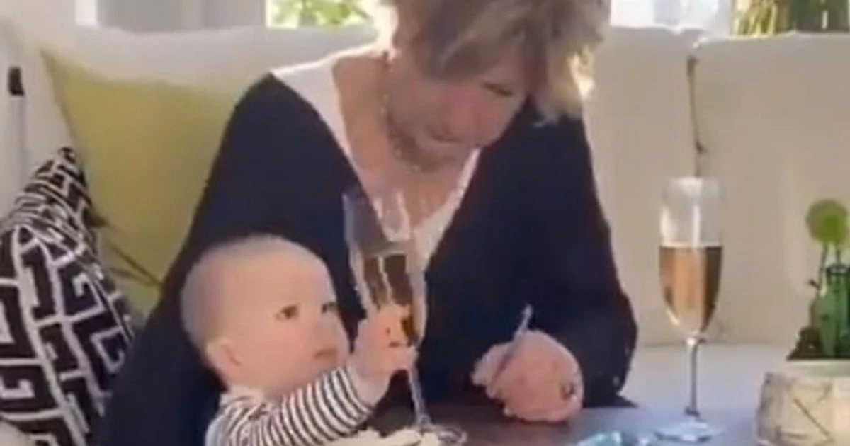 Grandmother lets her grandchild fall to the floor to save her glass of fizz