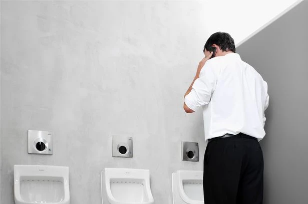 Men so obsessed with phones that they are now experts at the 'one handed wee'